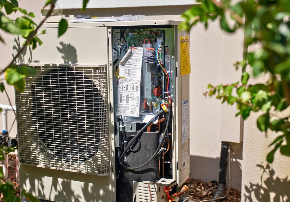 An open outdoor AC unit showing exposed internal wiring and components, relevant to evaluating whether to repair or replace the system.